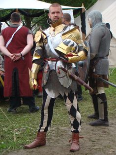 a man dressed in armor standing next to other men