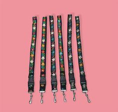 four lanyards with flowers on them against a pink background