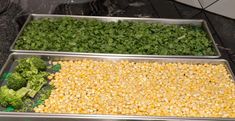 three metal trays filled with different types of vegetables on top of a counter next to each other