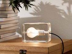 a light bulb sitting in a glass container on a table next to a stack of books