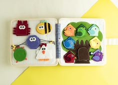 two small trays filled with felt toys on top of a yellow and white surface