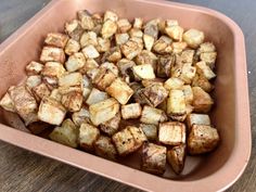 a pink bowl filled with cooked potatoes on top of a wooden table