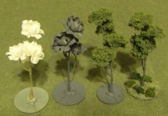 three small trees and two smaller ones on a table with green carpeted flooring