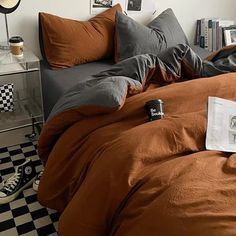 a bed with brown sheets and pillows in a bedroom next to a checkered floor