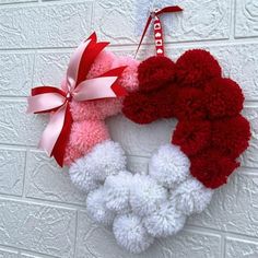 a red and white wreath hanging on a brick wall