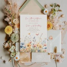 the wedding stationery is surrounded by flowers