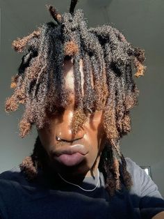 a young man with dreadlocks and ear buds on his ears is looking at the camera