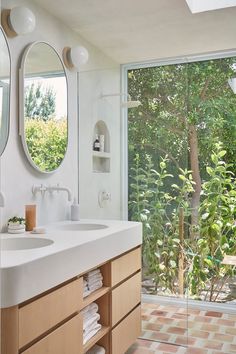 a bathroom with two sinks and mirrors in front of a large sliding glass door that leads to the outside