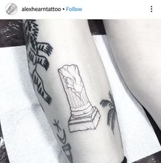 a woman's leg with tattoos on it and a statue in the middle of her leg