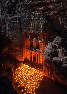 a cave with candles lit up in the floor and on the walls, surrounded by large rocks