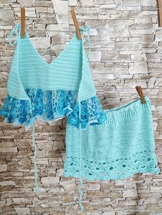 two crocheted bras hanging on clothes pins against a brick wall, one in blue and the other in aqua