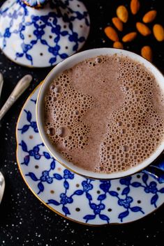 there is a cup of hot chocolate on the plate with spoons next to it