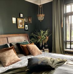 a bedroom with green walls and pillows on the bed, along with a chandelier