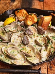 a pan filled with clams and bread on top of a wooden table