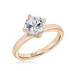 a rose gold engagement ring with an oval cut diamond in the center and two clawed shoulders