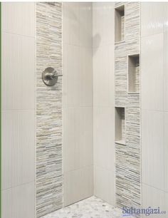 a walk in shower sitting next to a white tiled wall with shelves on each side