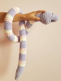 a person holding a knitted snake in their hand