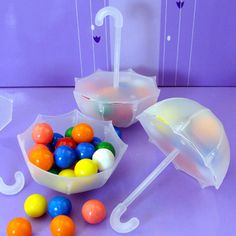 two plastic fillable umbrellas are next to some candy balls and one is filled with them