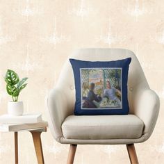 a white chair with a blue pillow on it next to a table and potted plant