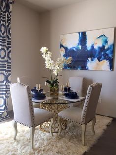 a dining room table with chairs and a painting on the wall