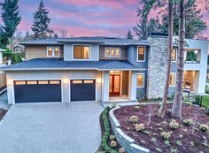 a large house with two garages in the front yard and trees on either side