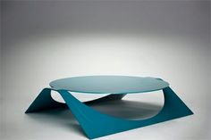 a blue coffee table sitting on top of a white floor next to a gray wall