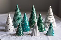 there are many small christmas trees on the white tablecloth, and one is made out of paper