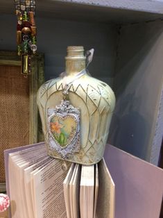 an open book with a bottle on top of it sitting next to some other books