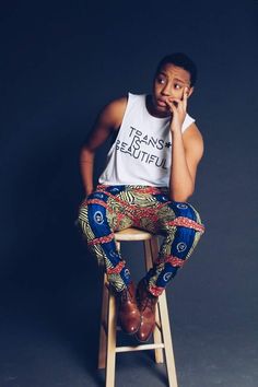 a man sitting on top of a stool talking on a cell phone while wearing patterned pants