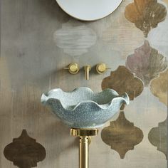 a bathroom sink sitting under a mirror next to a wall mounted faucet in front of a painting