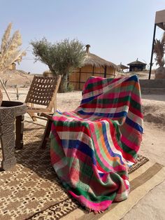 a blanket is laying on the ground next to a chair and table with a potted plant