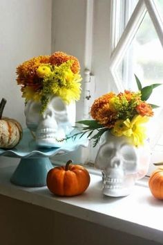 there are two vases with flowers in them on the window sill next to pumpkins