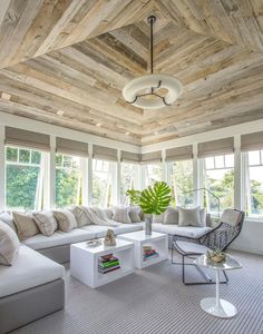 a living room filled with furniture and windows covered in wood planks on the ceiling