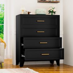 a black dresser with gold handles in a white living room next to a chair and window