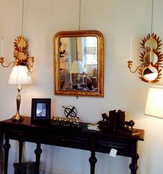 a table with two lamps and a mirror hanging on the wall above it in a room