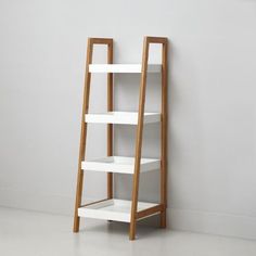 a white shelf with three shelves on each side and a wooden ladder leaning against the wall