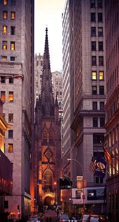 a city street filled with traffic and tall buildings at dusk, surrounded by tall skyscrapers