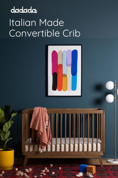 a baby crib in front of a blue wall with the words italian made convertible crib