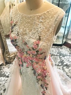 a dress with flowers on it sitting on a mannequin in front of a mirror