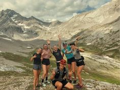 a group of people standing on top of a rocky hill with their arms in the air