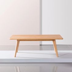 a wooden table sitting on top of a white floor next to a wall and window