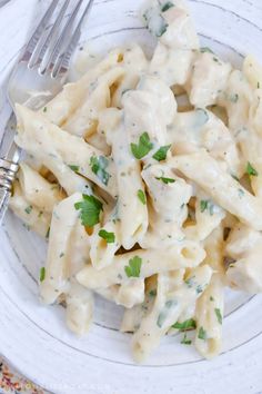 a white plate topped with pasta covered in sauce and parsley