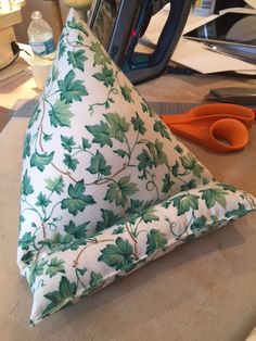 a green and white pillow sitting on top of a wooden table next to a pair of scissors