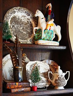 a wooden shelf filled with china and figurines on top of bookshelves