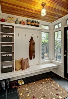 a white bench sitting under a window next to a black door and some shelves with items on it