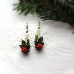 two small christmas decorations are hanging from earrings