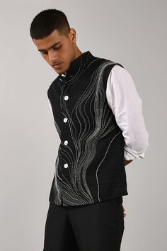 Black bundi with placement thread work and front button closure.
Components:1
Embroidered
Neckline:Mandarin Collar
Sleeve Length:Sleeveless
Fabric:Cotton Silk
Color:Black
Chest welt pocket
Closure: Front buttons
Note: Inner shirt and pant worn by the model is not for sale - Aza Fashions Luxury Men's Nehru Jacket With Dori Work, Luxury Men's Nehru Jacket With Dupatta, Luxury Men's Nehru Jacket With Dabka, Luxury Men's Nehru Jacket For Diwali, Luxury Menswear-inspired Semi-formal Outerwear, Luxury Reception Sets With Mandarin Collar, Luxury Men's Jamawar Nehru Jacket, Luxury Men's Outerwear With Resham Embroidery, Luxury Men's Nehru Jacket In Traditional Drape