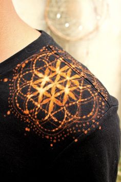 a close up of a person wearing a black shirt with an orange design on it