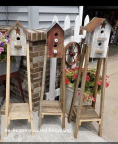 three birdhouses made out of bricks and wood are sitting next to each other on the sidewalk