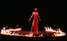 a woman in red dress standing on fire